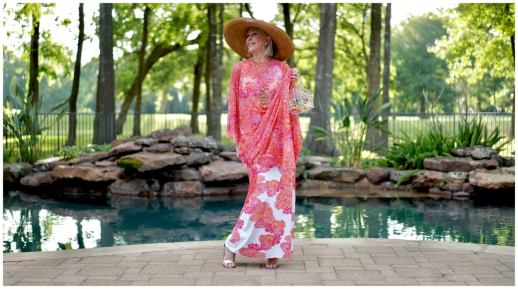 Sheree Frede of the SheShe Show by swimming pool wearing a coral floral kaftan