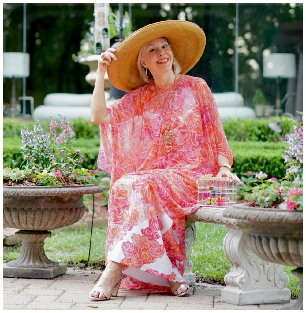 Sheree Frede of the SheShe Show sitting by on a bench wearing a coral floral kaftan