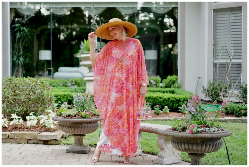 Sheree Frede of the SheShe Show standing by on a bench wearing a coral floral kaftan