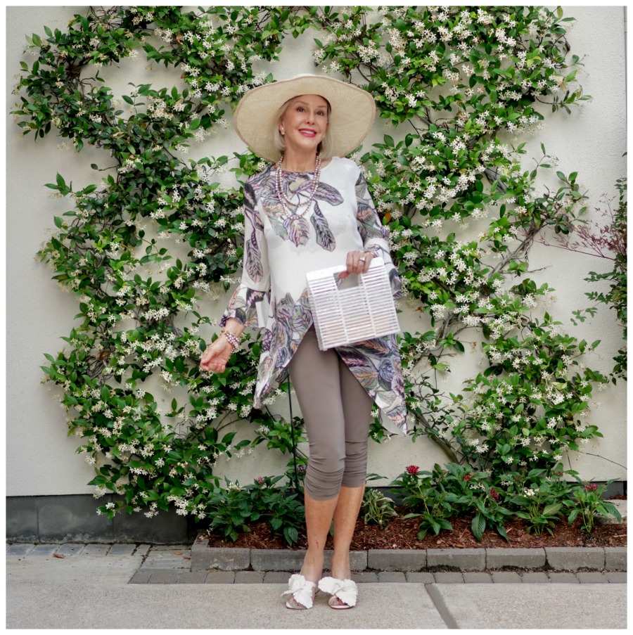 Sheree Frede of the SheShe Show standing in front of jasmine vine wall wearing print top over leggings