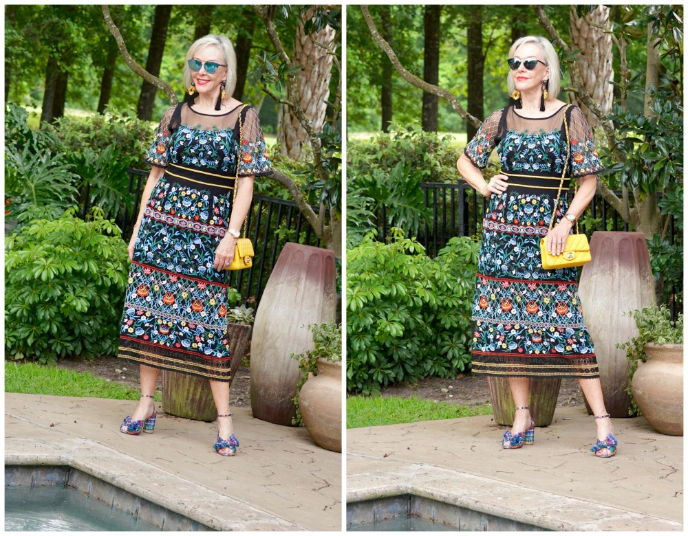 Sheree Frede of the SheShe Show standing by swimming pool wearing sunglasses and a black floral dress