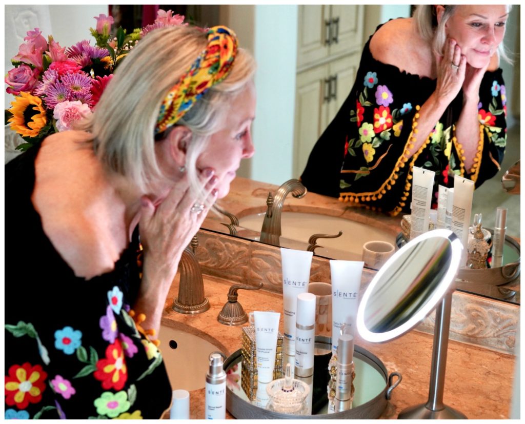 Sheree Frede founder of the SheSheShow applying Sente skincare in her bathroom wearing a black floral offtheshoulder top