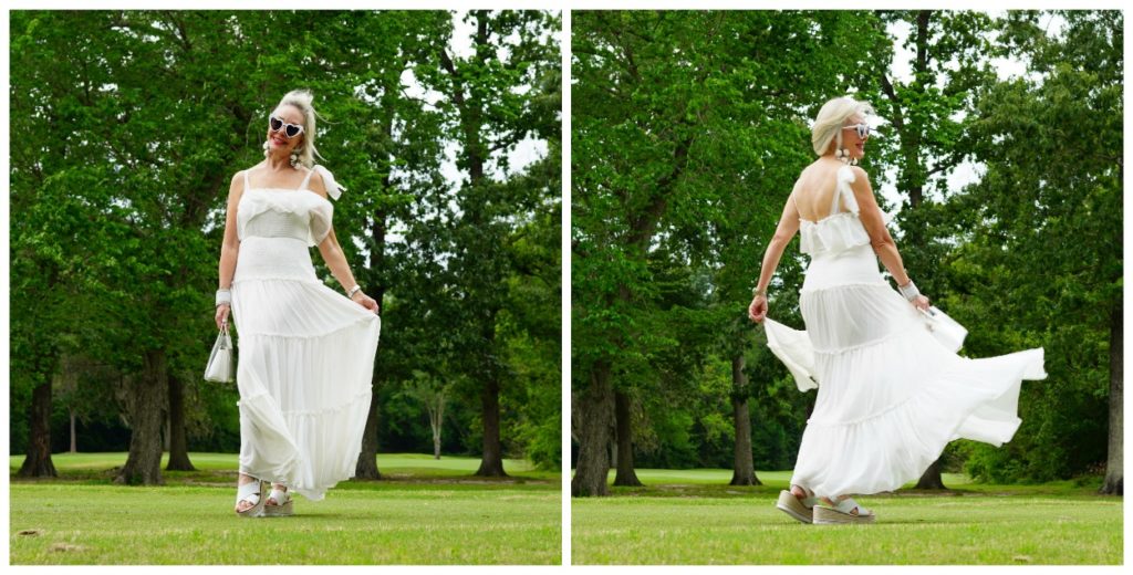 Sheree Frede of the SheShe Show wearing a white flowy maxi dress on a green lawn and wooded background