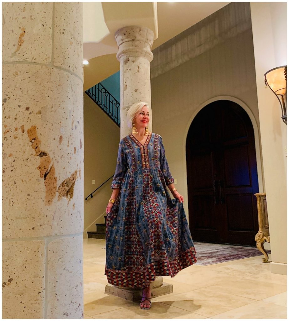 Sheree Frede of the SheShe Show standing in foyer by column wearing a chambray maxi dress accented in embellishments