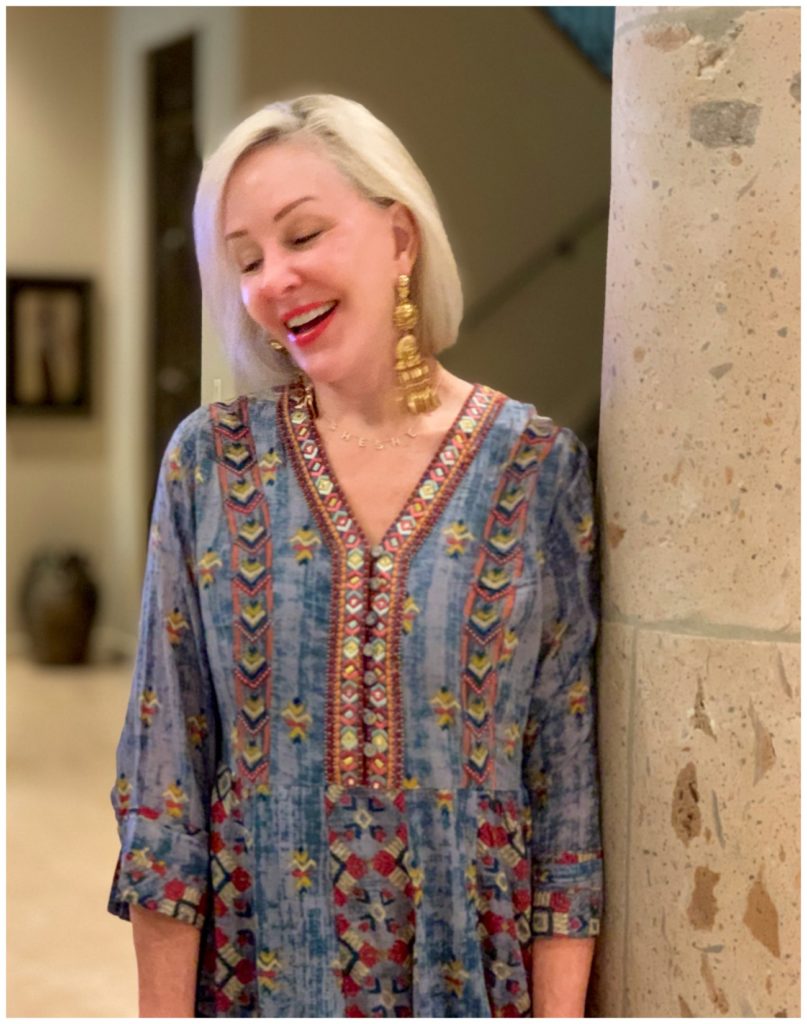 Sheree Frede of the SheShe Show standing in foyer by column wearing a chambray maxi dress accented in embellishments