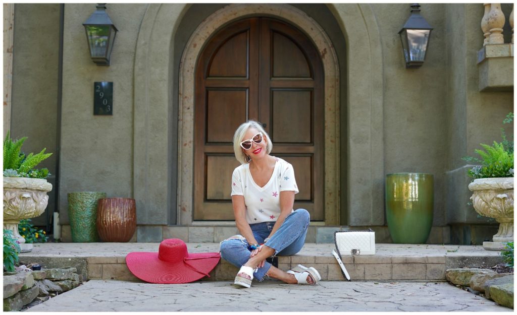 sheree of the SheSheShow sitting in front of house wearing ripped jeans and white star tee shirt