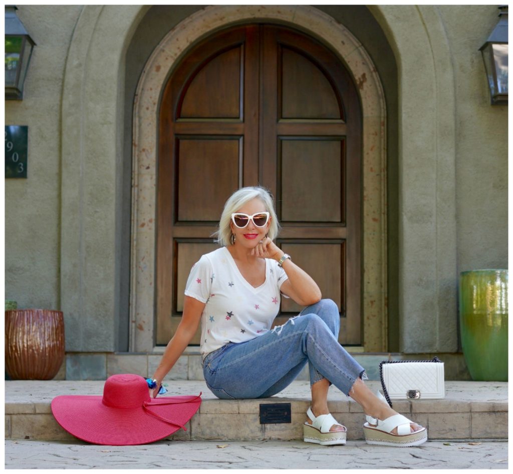 sheree of the SheSheShow sitting in front of house wearing ripped jeans and white star tee shirt