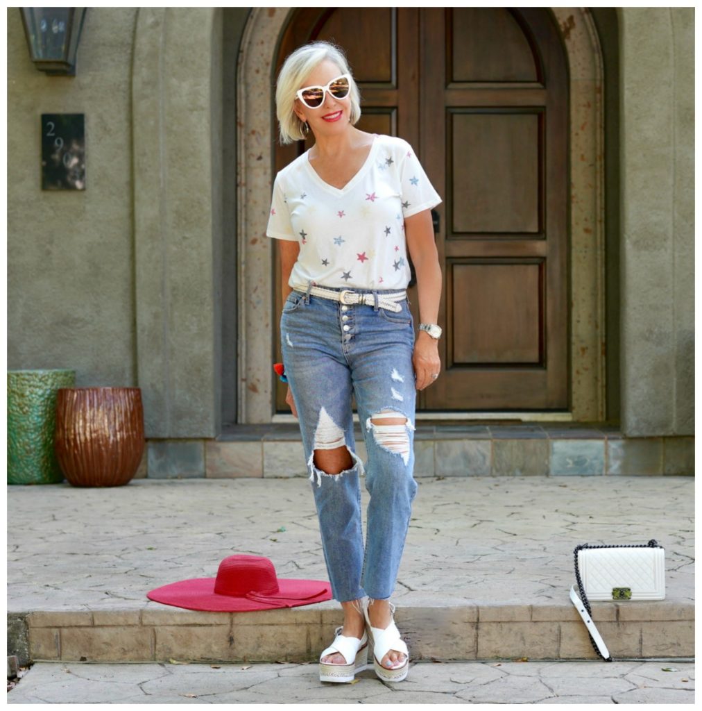 sheree of the SheSheShow sitting in front of house wearing ripped jeans and white star tee shirt