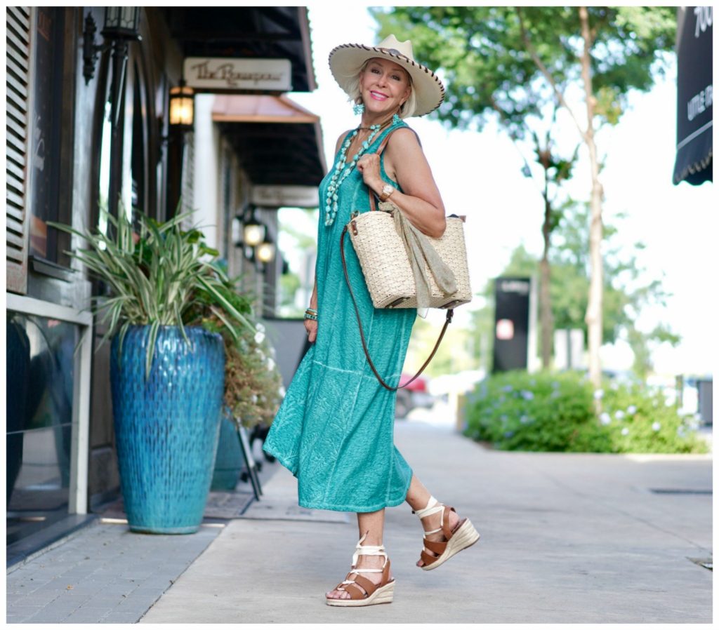 Sheree Frede of the SheShe Show walking down alley wearing green dress carrying straw toter