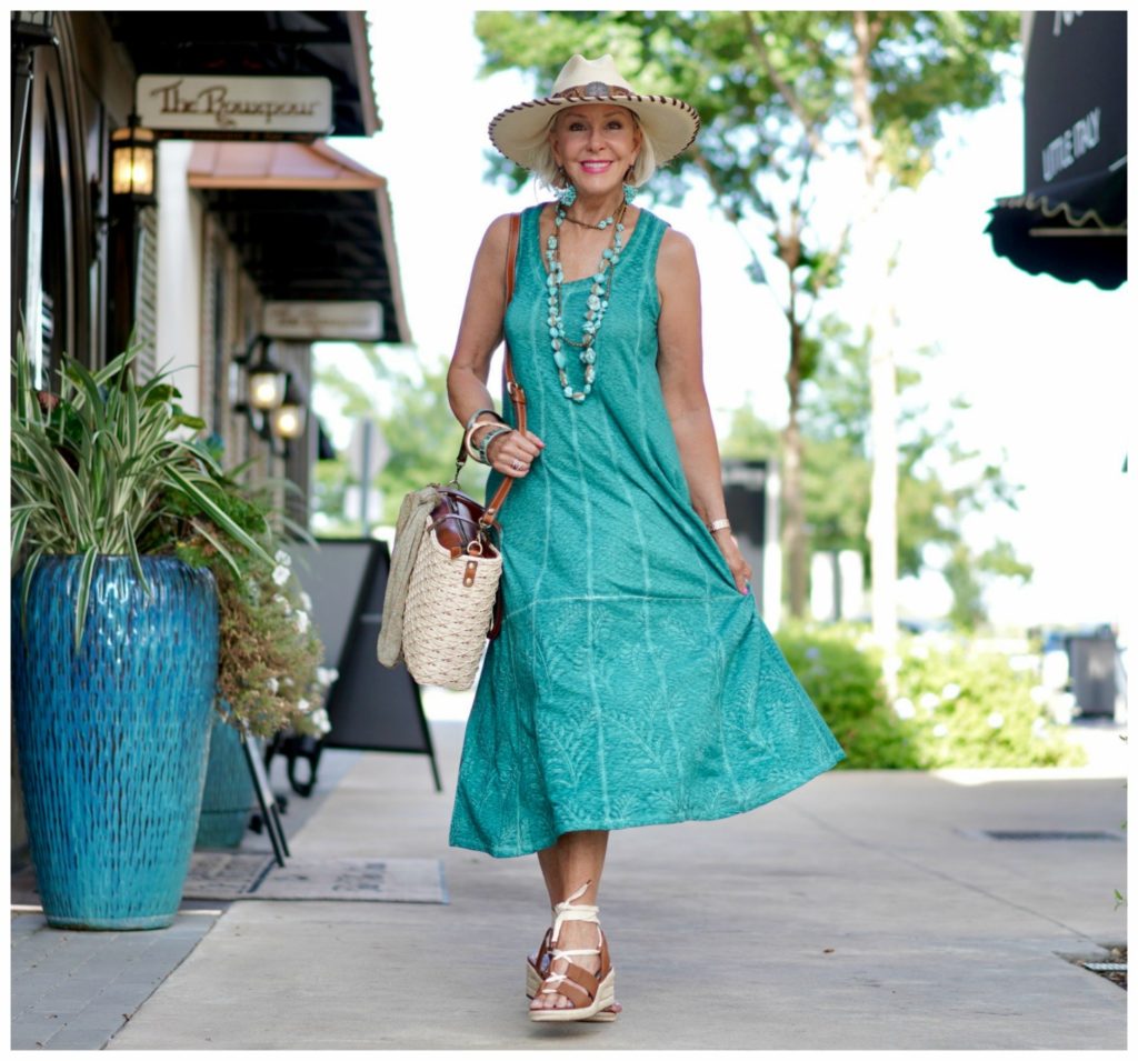 Sheree Frede of the SheShe Show walking down alley wearing green dress carrying straw toter