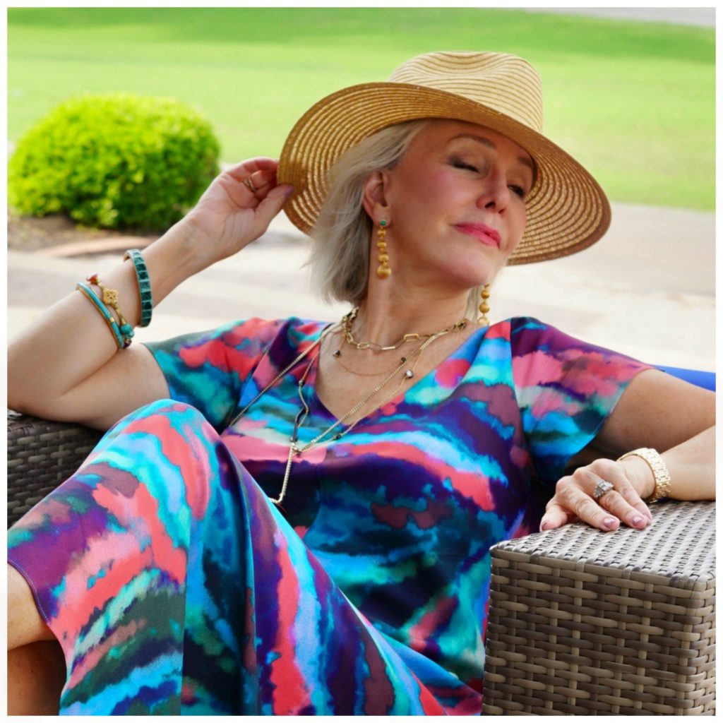 Sheree of the SheShe Show wearing multi colored dress with hat and layered necklaces