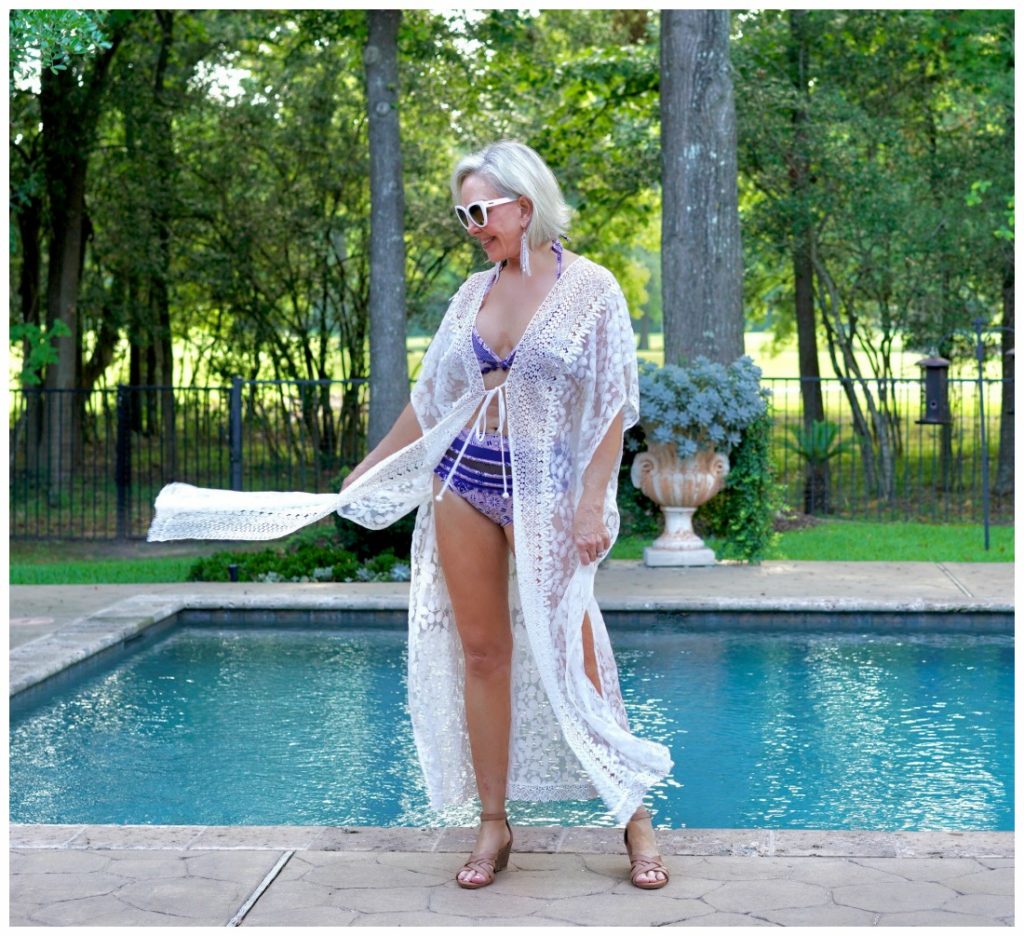 Sheree Frede of the SheSheSHow by swimming pool wearing white long lace swimsuit cover-ups over 2 pc swimsuit