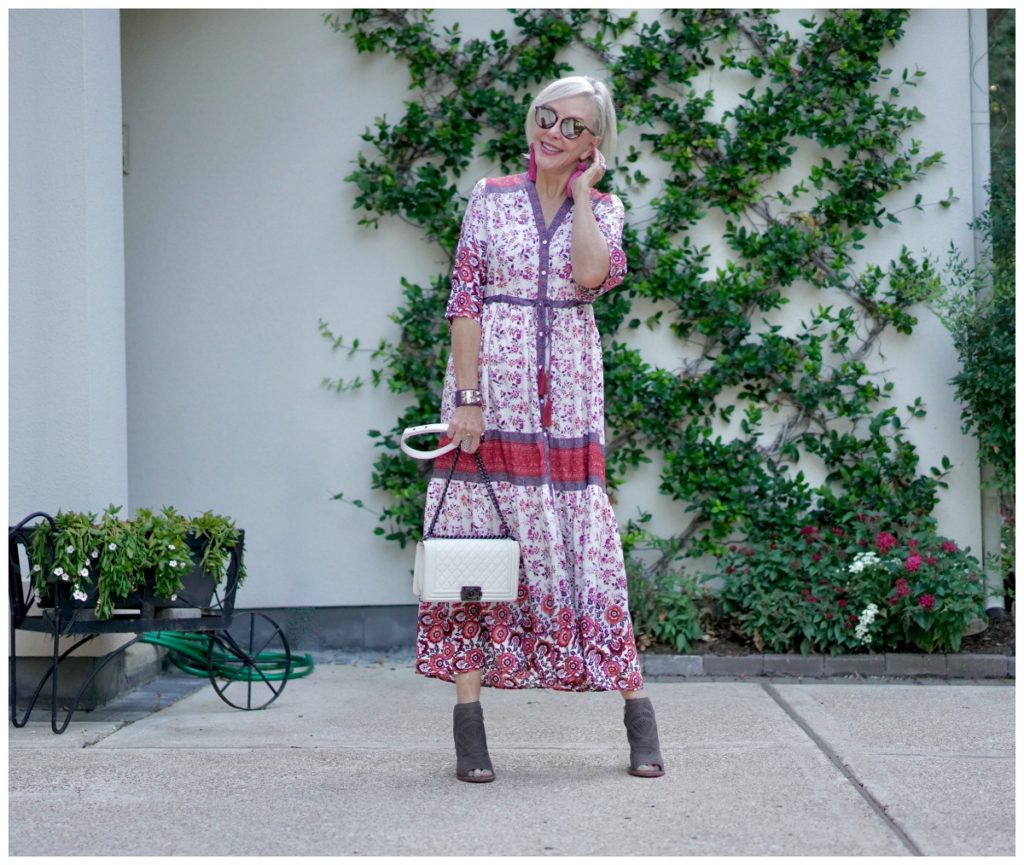 Sheree Frede of the SheSheShow standing in front of trellis wall wearing a maxi red and white floral dress - instagram