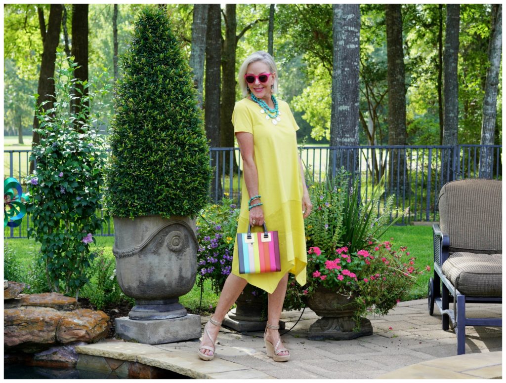 Sheree Frede of the SheShe Show stand in a flower garden wearing a yellow dress