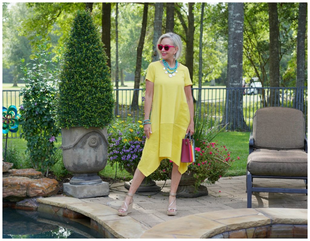 Sheree Frede of the SheShe Show stand in a flower garden wearing a yellow dress