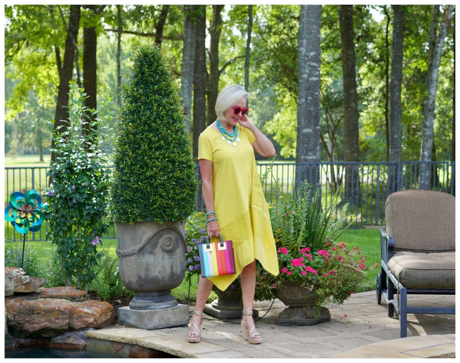 Sheree Frede of the SheShe Show stand in a flower garden wearing a yellow dress