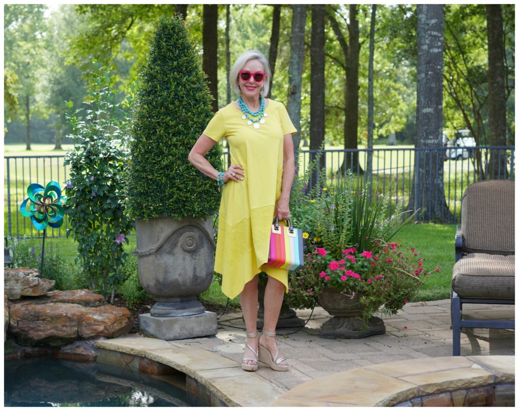 Sheree Frede of the SheShe Show stand in a flower garden wearing a yellow dress