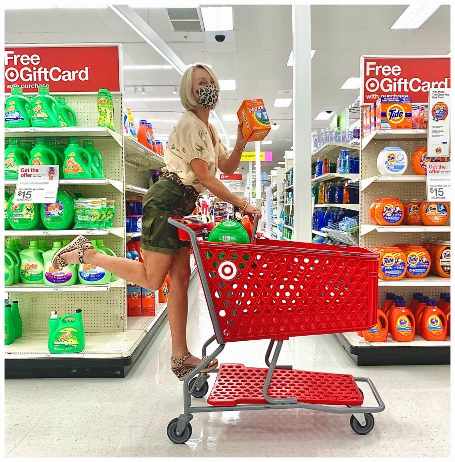 Sheree Frede of the SheShe Show wearing camo shorts riding a grocery cart  in the laundry aisle at Target holding Bounty