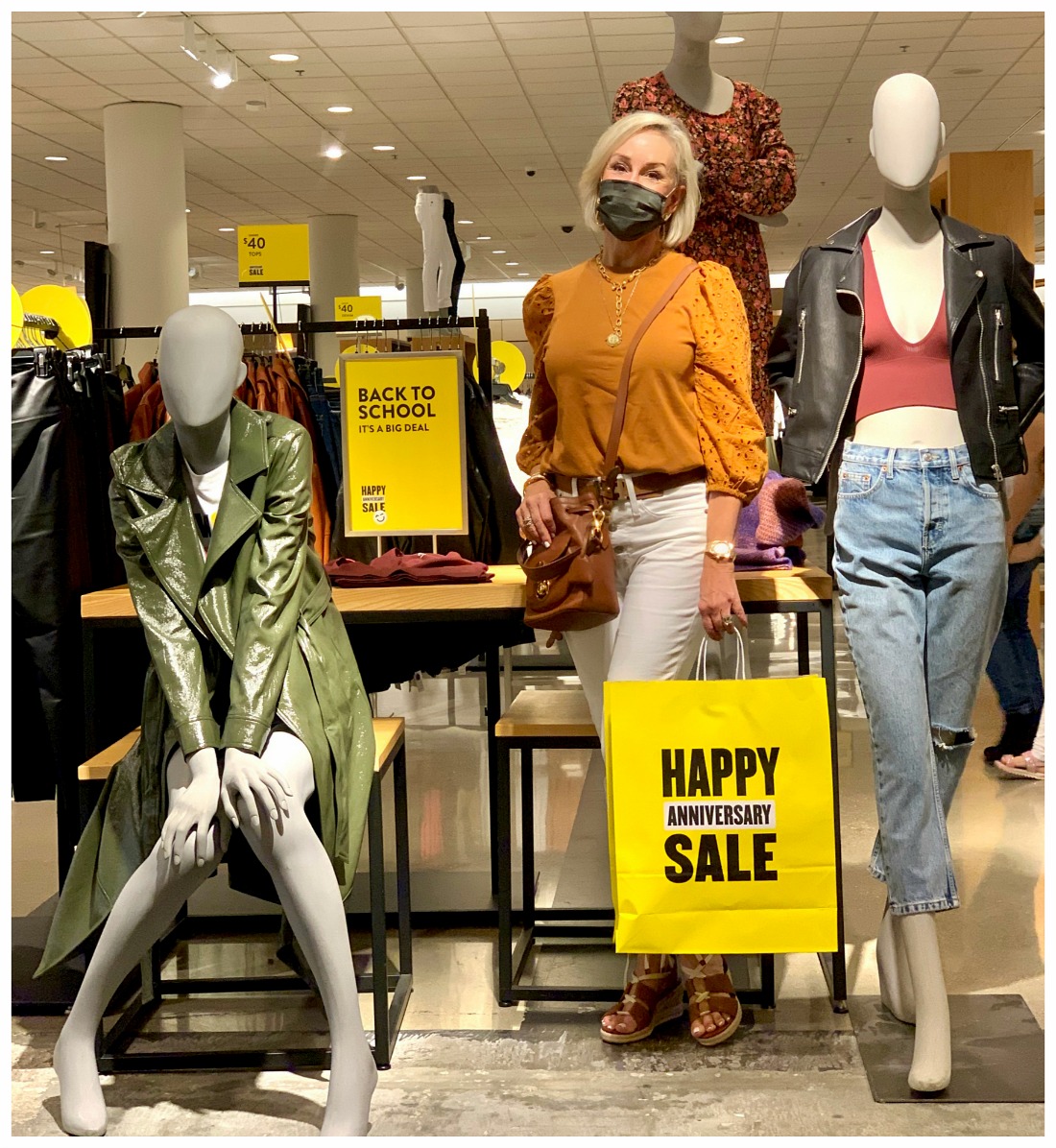 Sheree Frede of the SheShe Show stand on platform with Nordstrom mannequins wearing a burnt orange eyelet top with white jeans