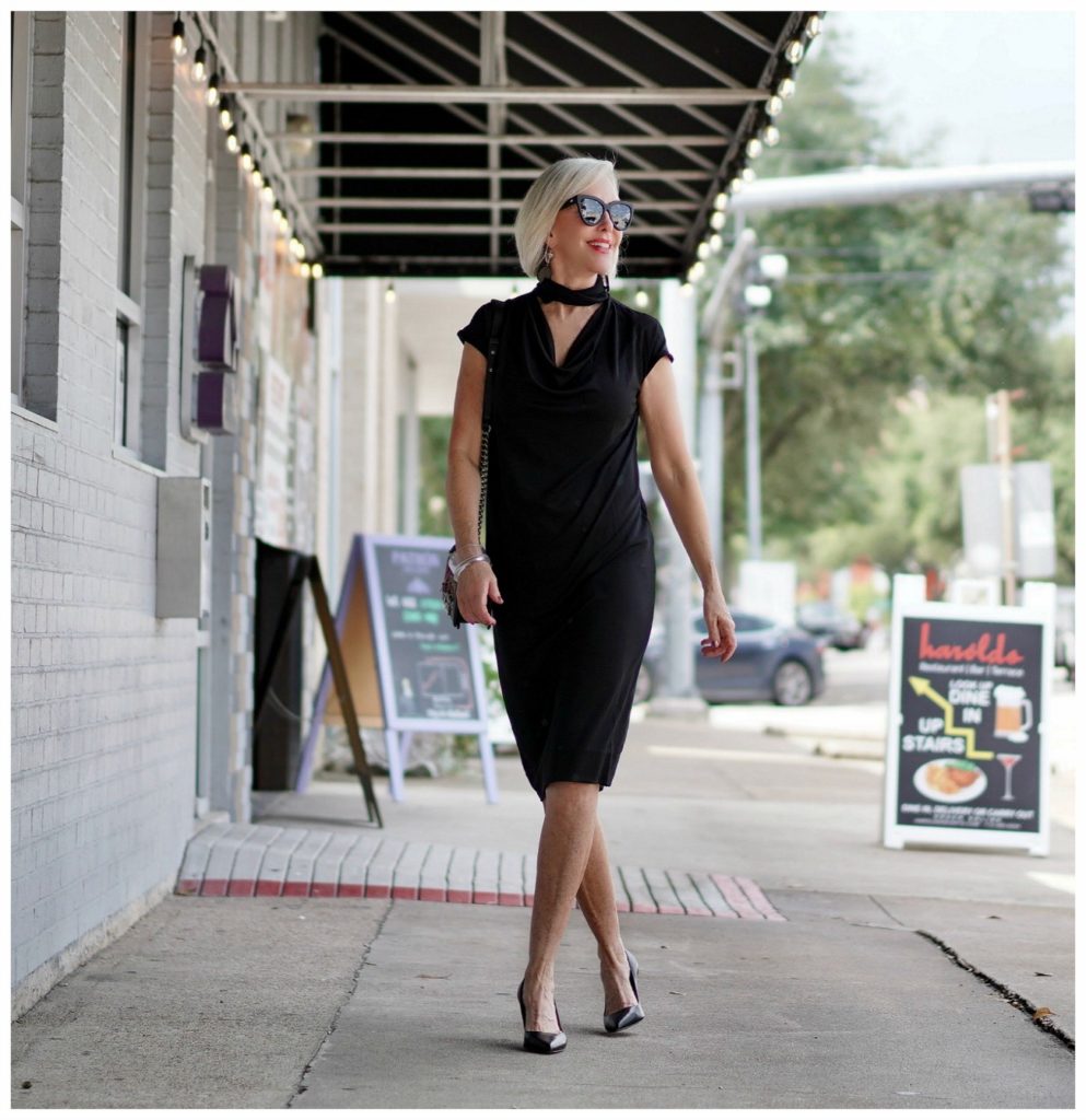 Sheree Frede of the SheShe Show standing in front of mural wall wearing a Chicos black shift dress