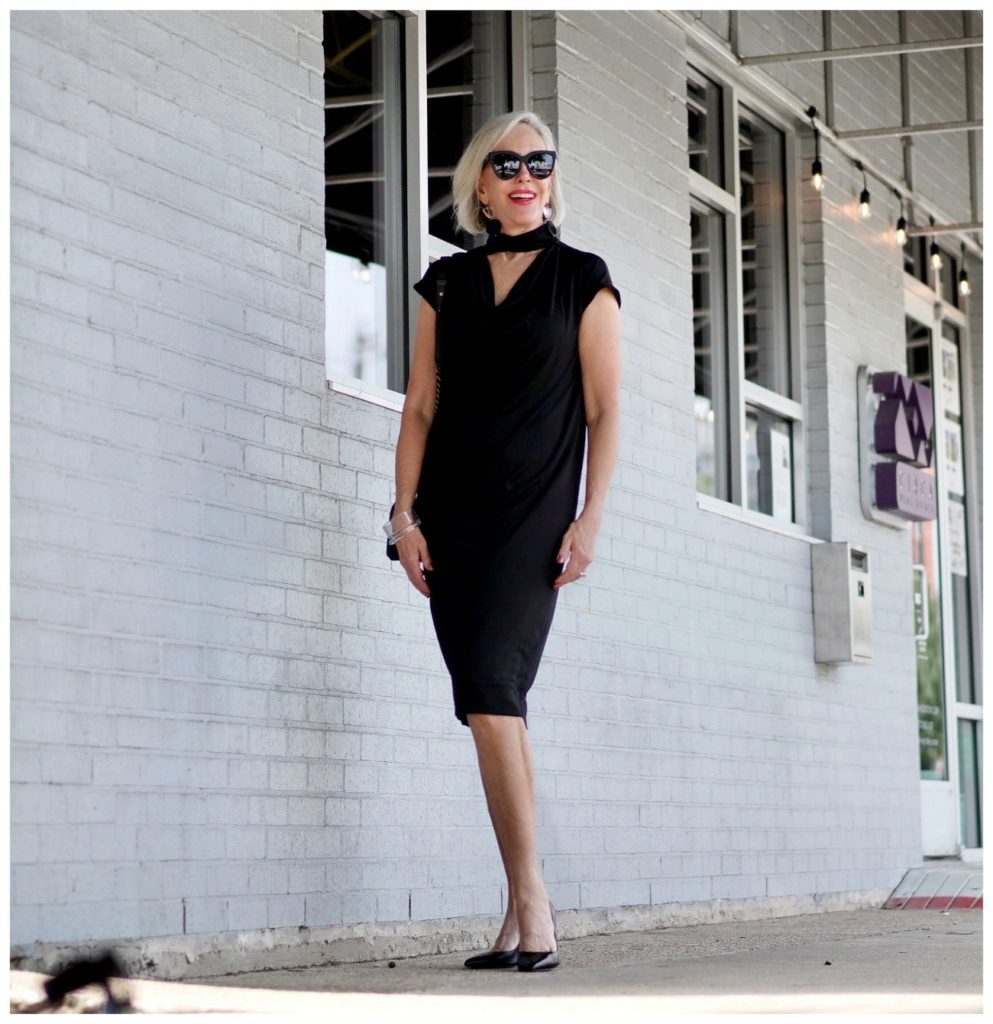 Sheree Frede of the SheShe Show standing in front of mural wall wearing a Chicos black shift dress