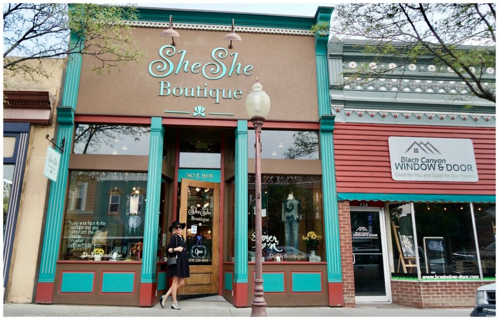 Sheree Frede of the SheSheShow standing in front of a door wearing an above the knee black dress