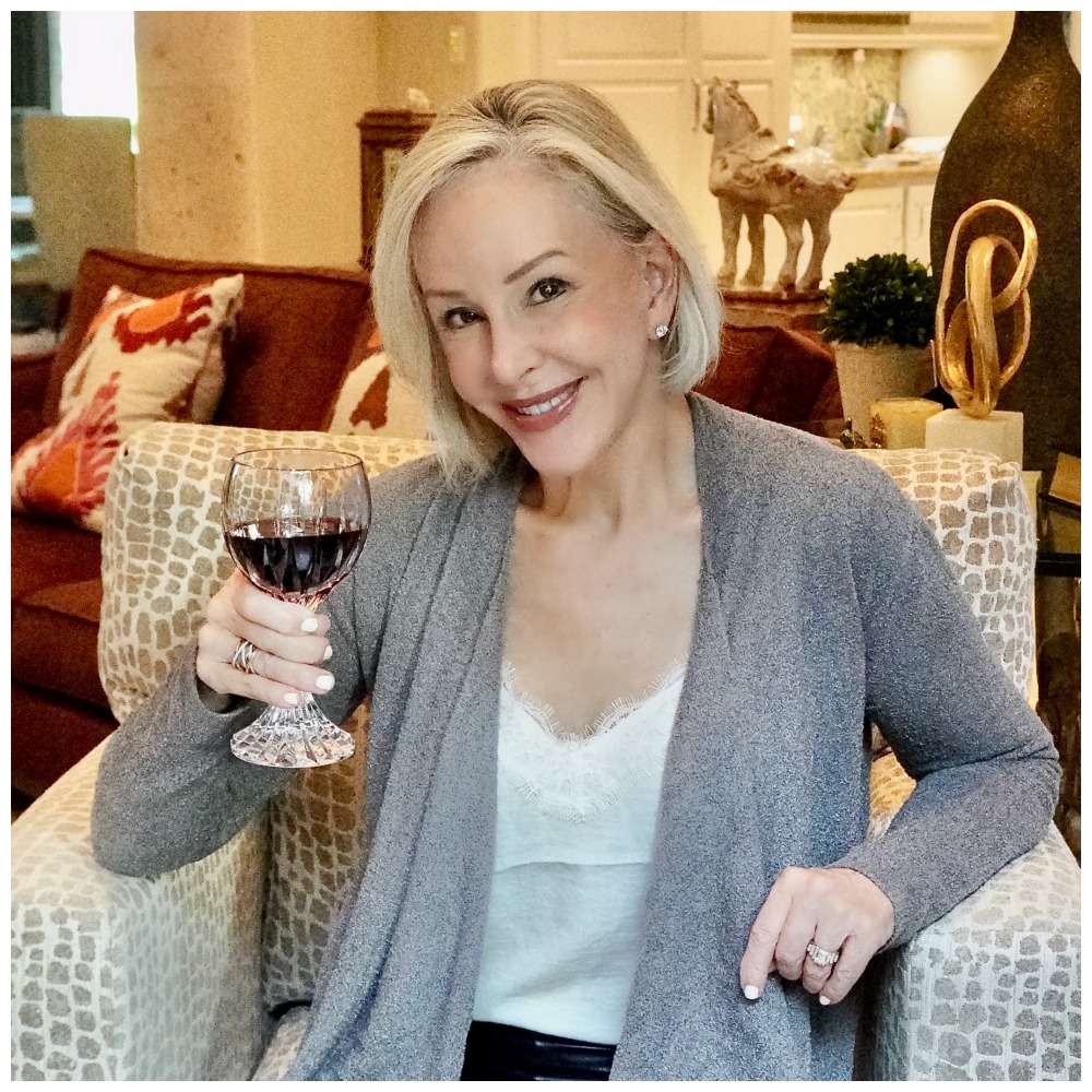 Sheree Frede of the SheShe Show sitting in a chair wearing black leggings and gray cardigan over a white camisole