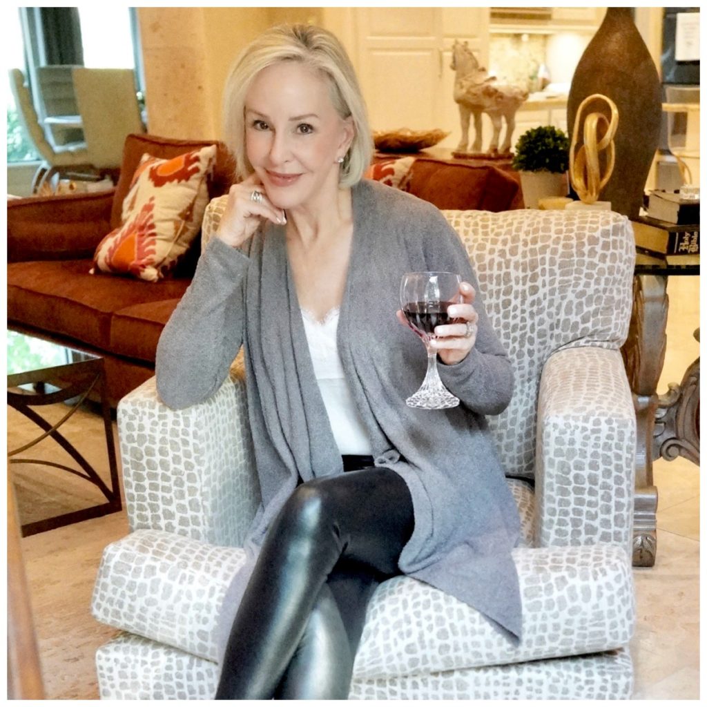 Sheree Frede of the SheShe Show sitting in a chair wearing black leggings and gray cardigan over a white camisole