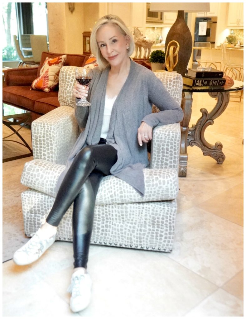 Sheree Frede of the SheShe Show sitting in a chair wearing black leggings and gray cardigan over a white camisole