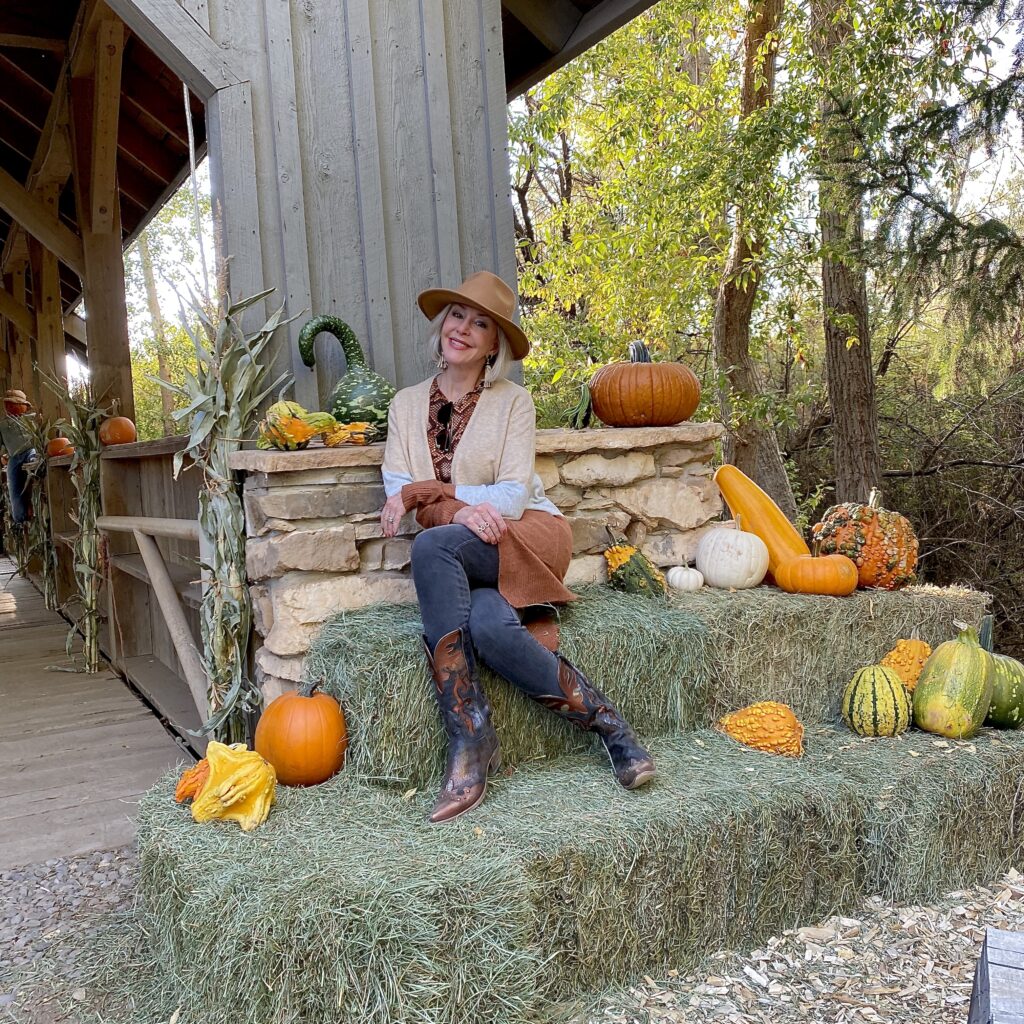 Sheree Frede of the SheShe Show wearing a knee length stripe cardigan sitting beside a covered bridge - October