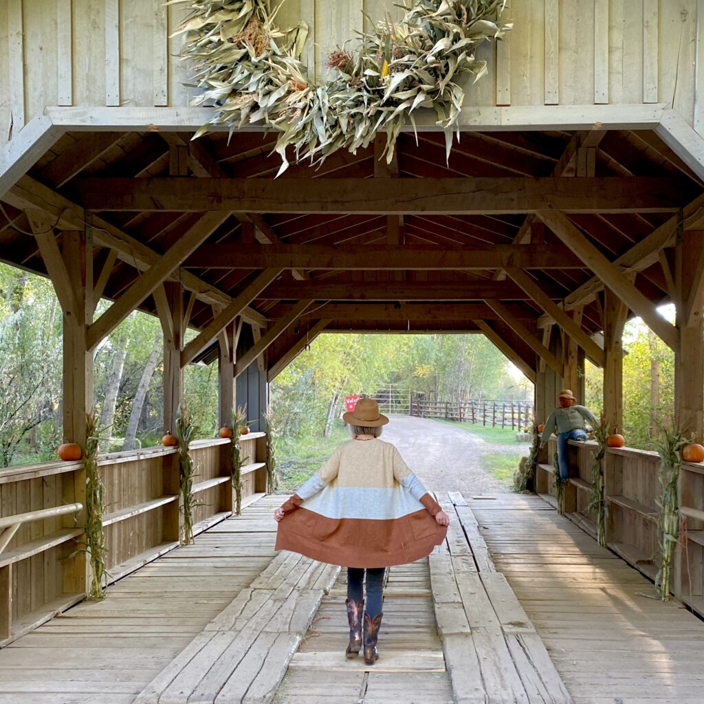 Sheree Frede of the SheShe Show wearing a knee length stripe cardigan walking across a covered bridge