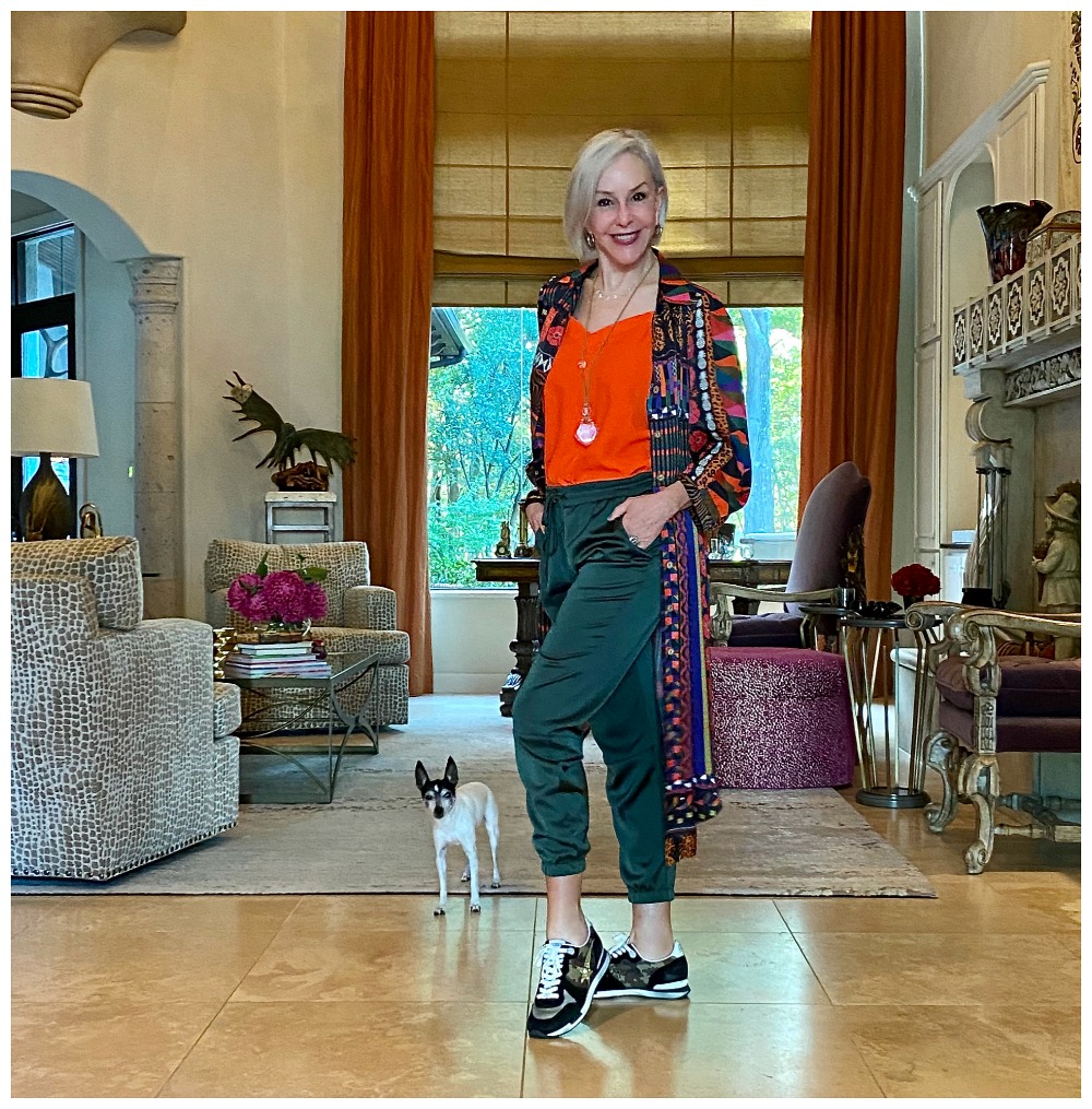 Sheree Frede of the SheShe Show standing in living room wearing green satin jogger pants and multi colored duster