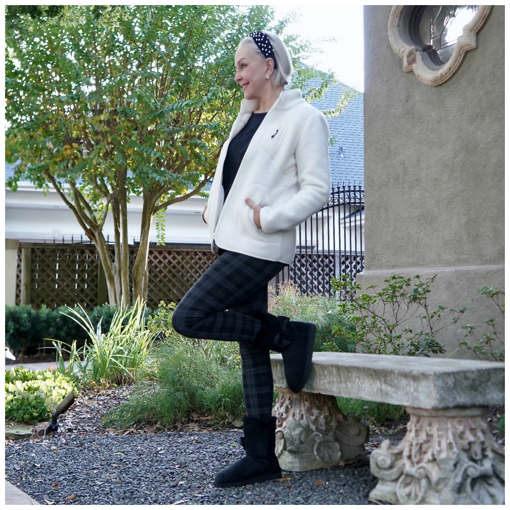 Sheree Frede of the SheShe Show sitting on a stone bench wearing a white sherpa and leggings