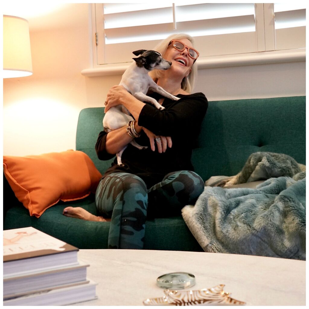 Sheree Frede of the SheShe Show sitting on a sofa with her dog Pippa wearing a black top and leggings