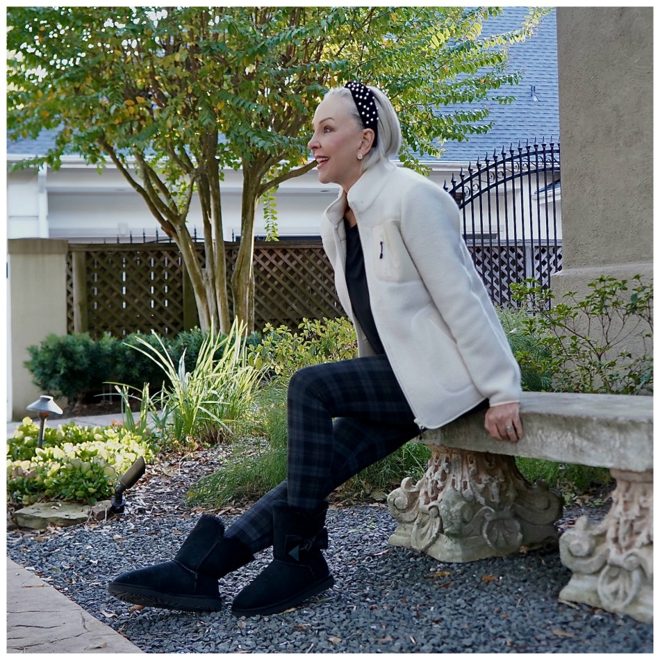 Sheree Frede of the SheShe Show sitting on a stone bench wearing a white sherpa and leggings