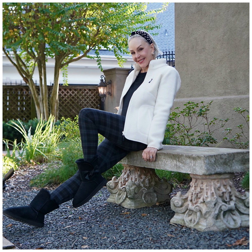 Sheree Frede of the SheShe Show sitting on a stone bench wearing a white sherpa and leggings