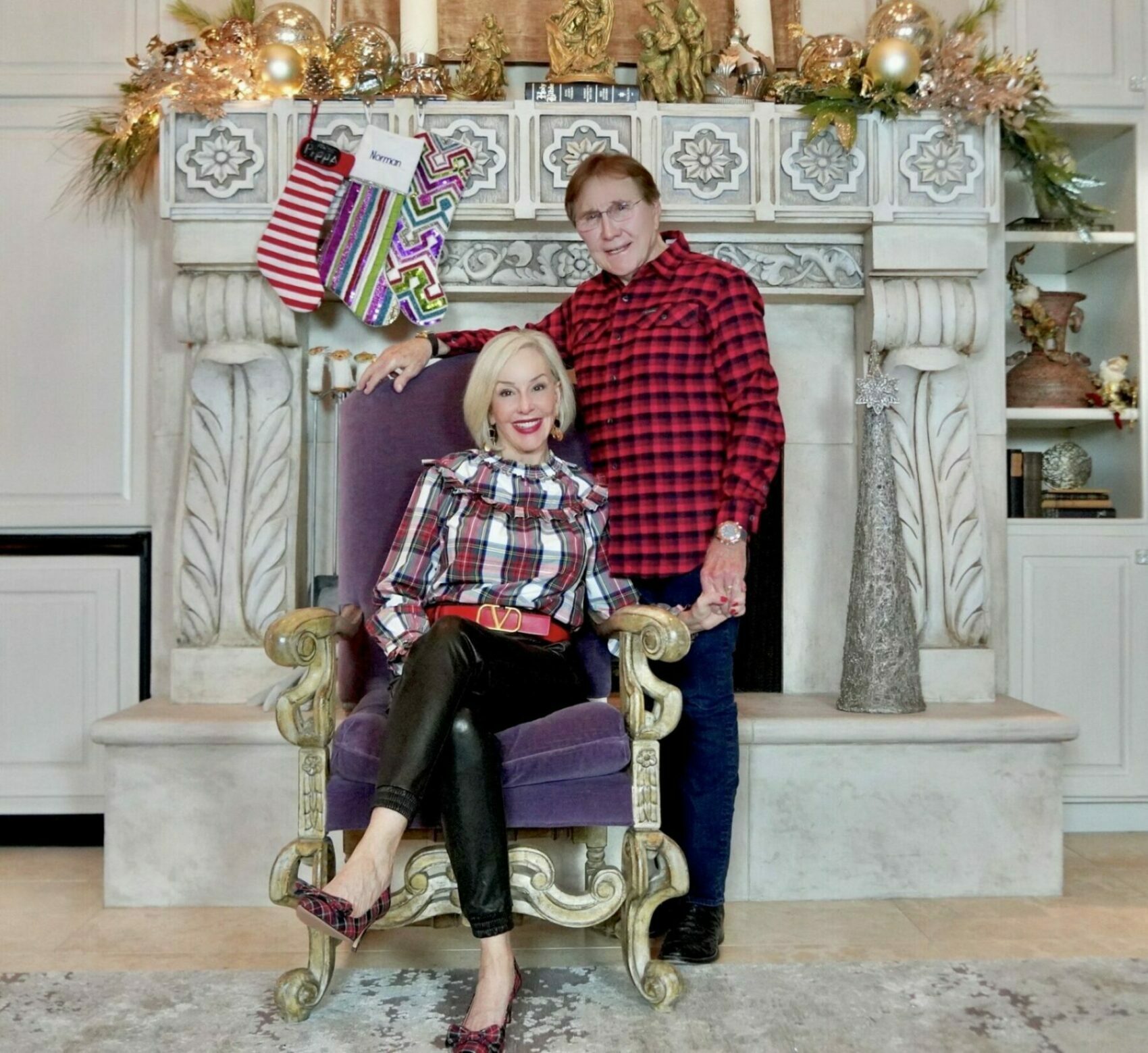 Sheree and Norman Frede in front of fireplace wearing holiday plaid