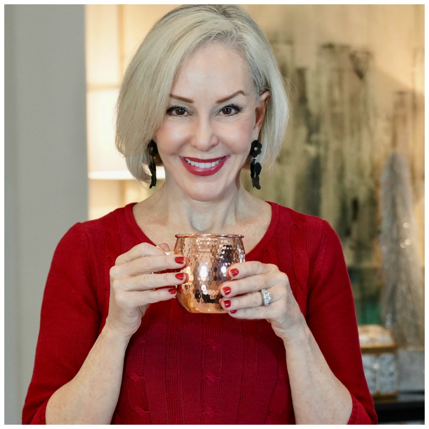 Sheree Frede of the SheShe SHow holding a copper cup wearing a red dress