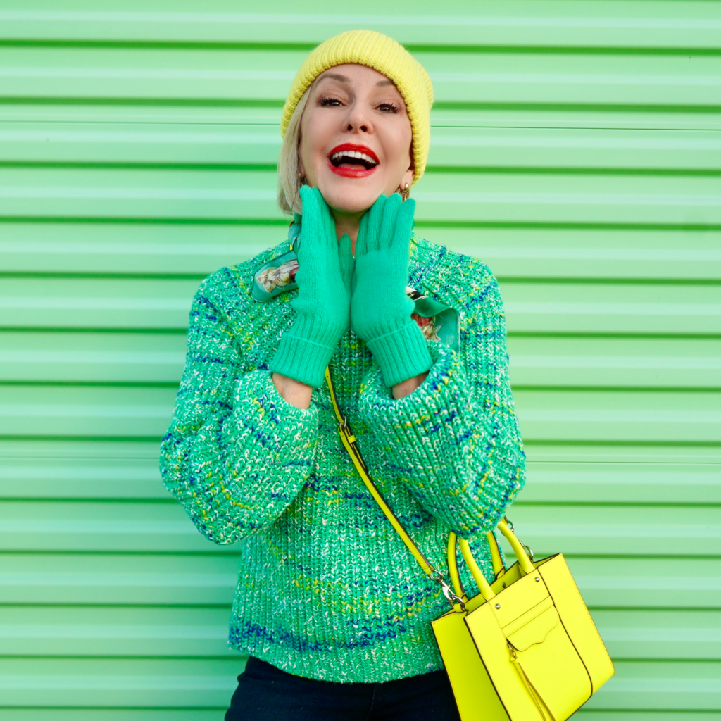 Sheree Frede of the SheShe Show standing in front of green door wearing a green sweater and chartreuse beanie