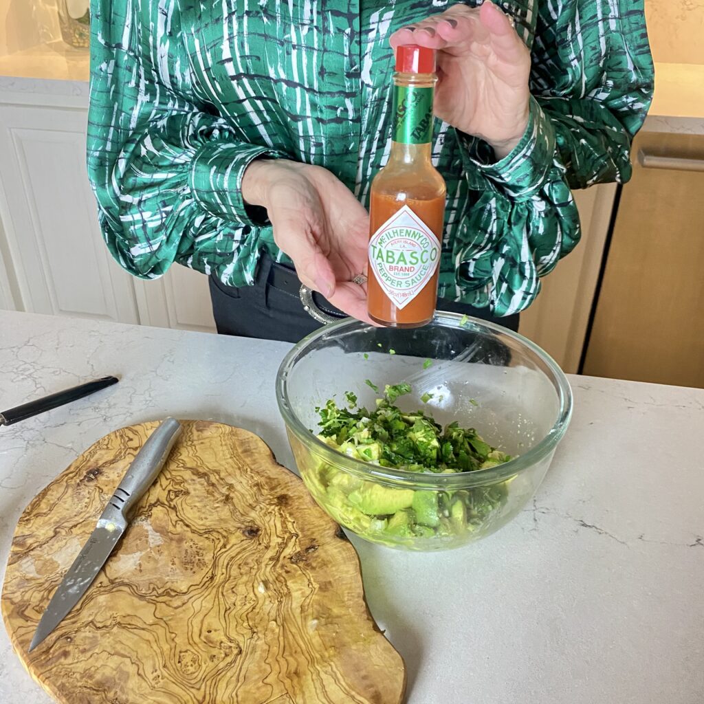 Sheree Frede of the SheShe Show in the kitchen making guacamole wearing a green print shirt