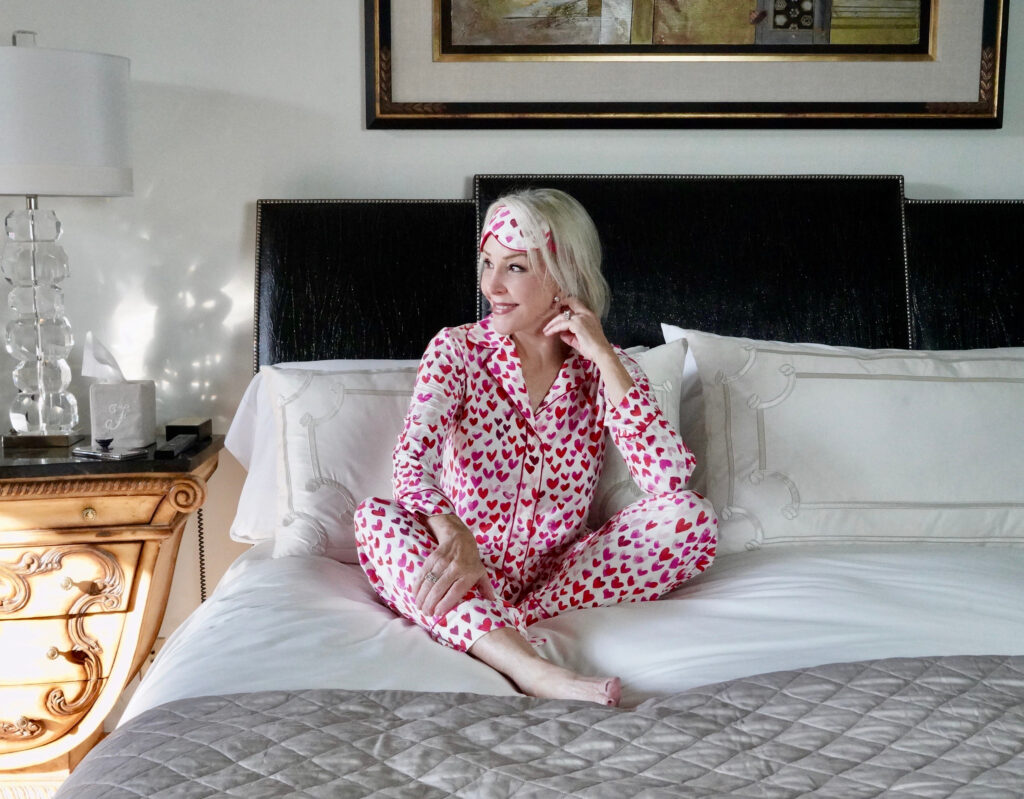Sheree Frede of the SheShe Show lounging on her bed in heart print pajamas