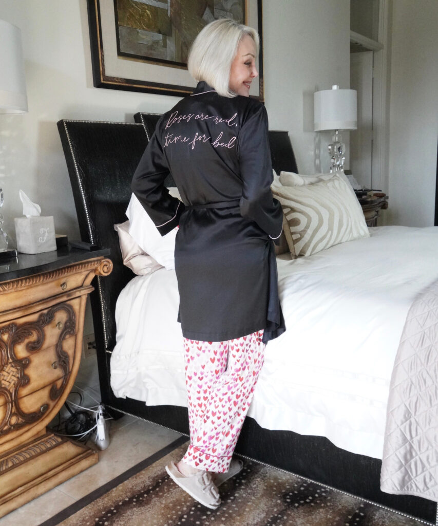Sheree Frede of the SheShe Show jumping up on her bed in heart print pajamas and black robe