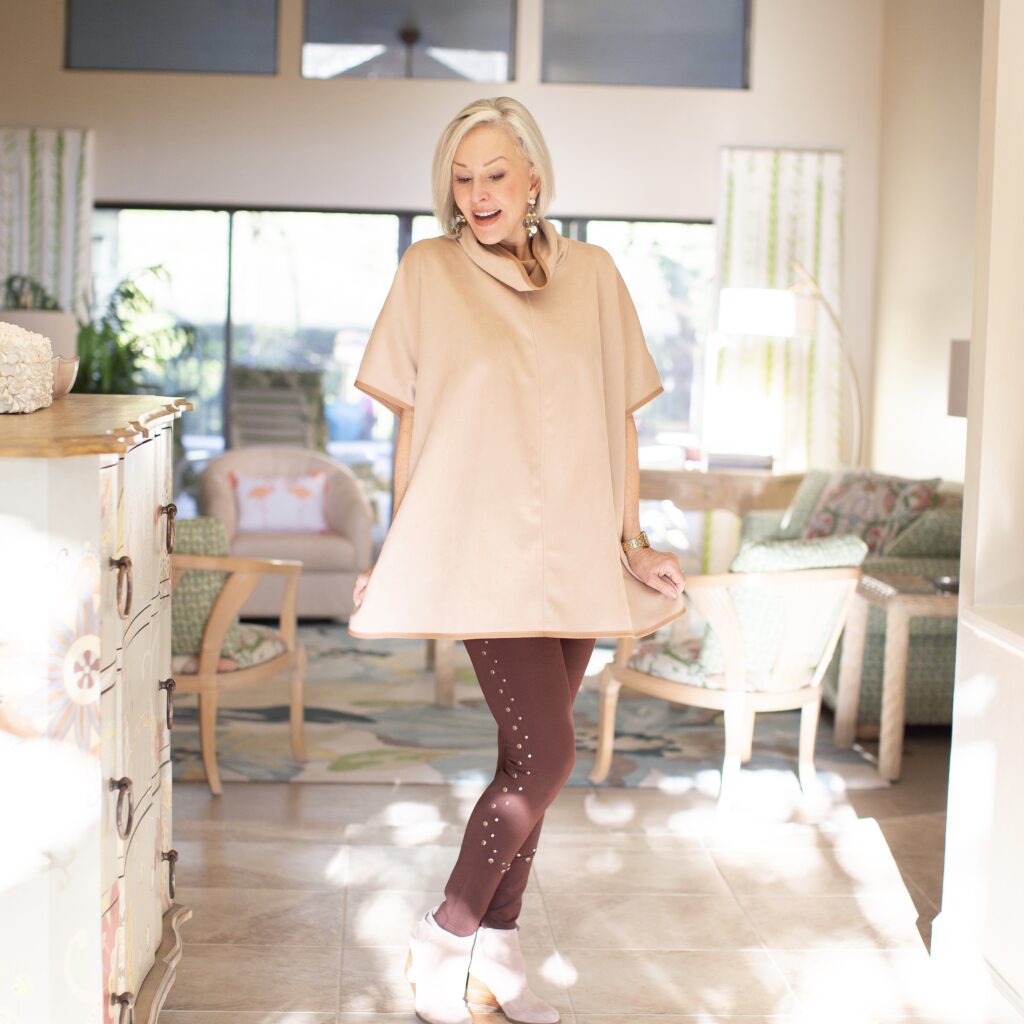Sheree Frede of the SheShe Show standin foyer wearing a tan poncho over brown studded leggings