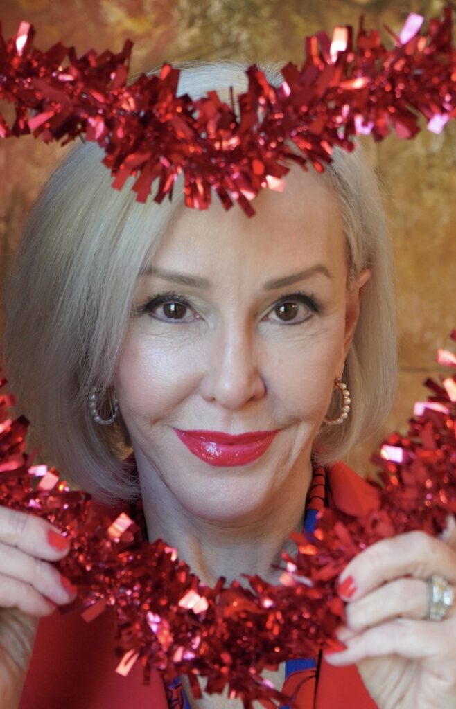 Sheree Frede dressed in red and red lipstick with ead framed in red tinsel heart season of love