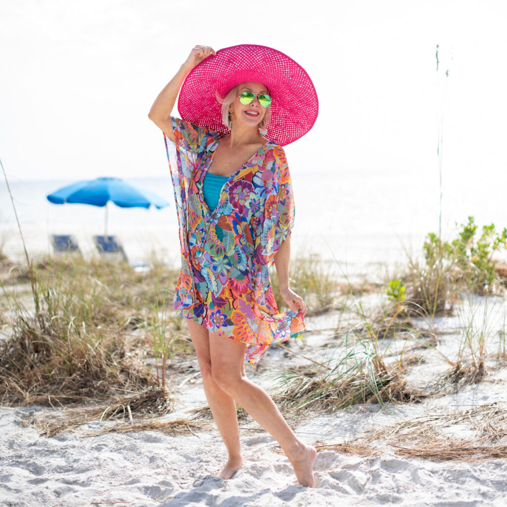 Sheree Frede of the SheSheShow multi colored print swimsuit coverup, kaftan, large hot pink hat, sunglasses, beach