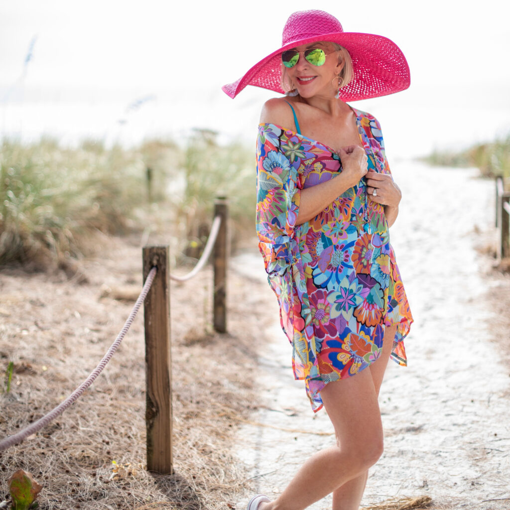 Sheree Frede of the SheSheShow multi colored print swimsuit coverup, kaftan, large hot pink hat, sunglasses, beach