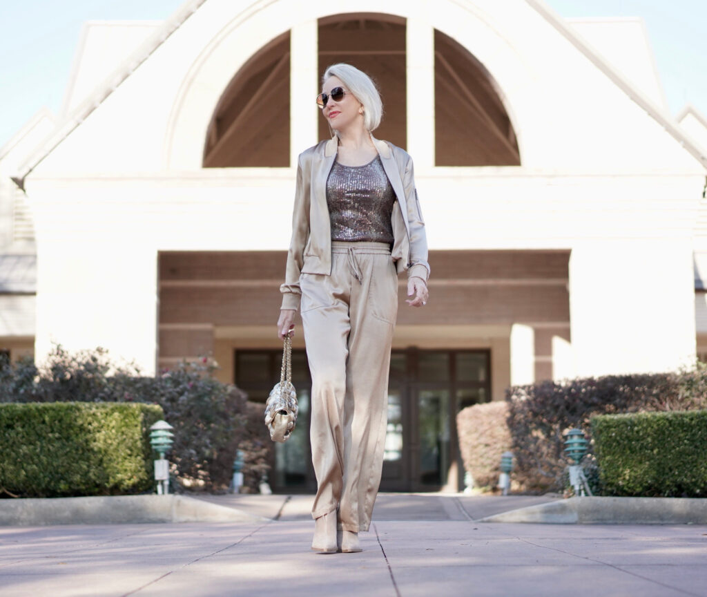 Sheree Frede of the SheShe Show wearing gold silk drawstring pants and bomber jacket with taupe suede booties