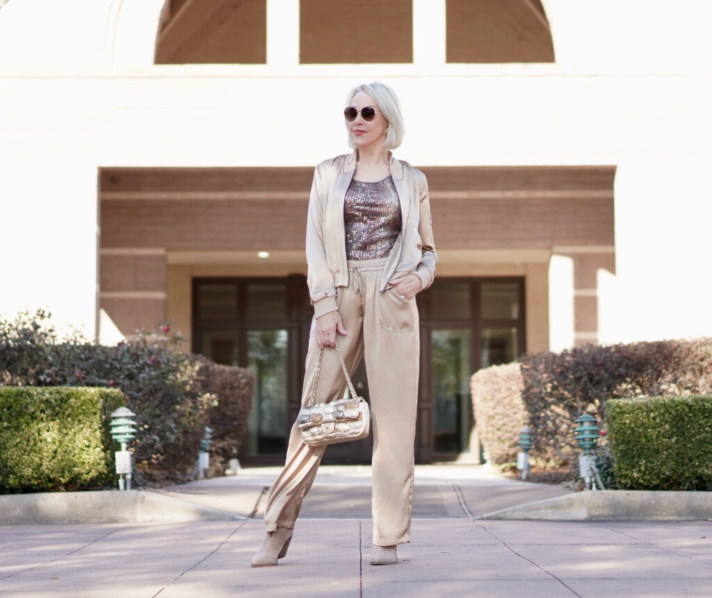 Sheree Frede of the SheShe Show wearing gold silk drawstring pants and bomber jacket with taupe suede booties