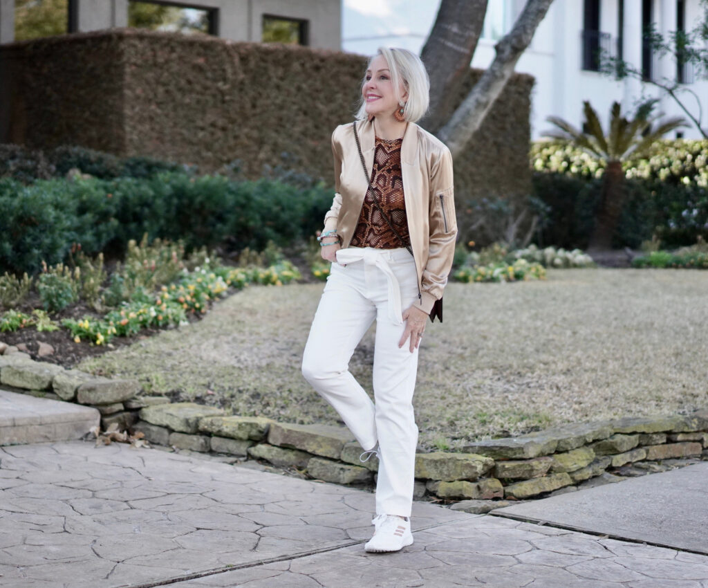 Sheree Frede of the SheShe Show white pants, gold silk bomber jacket standing in front of house