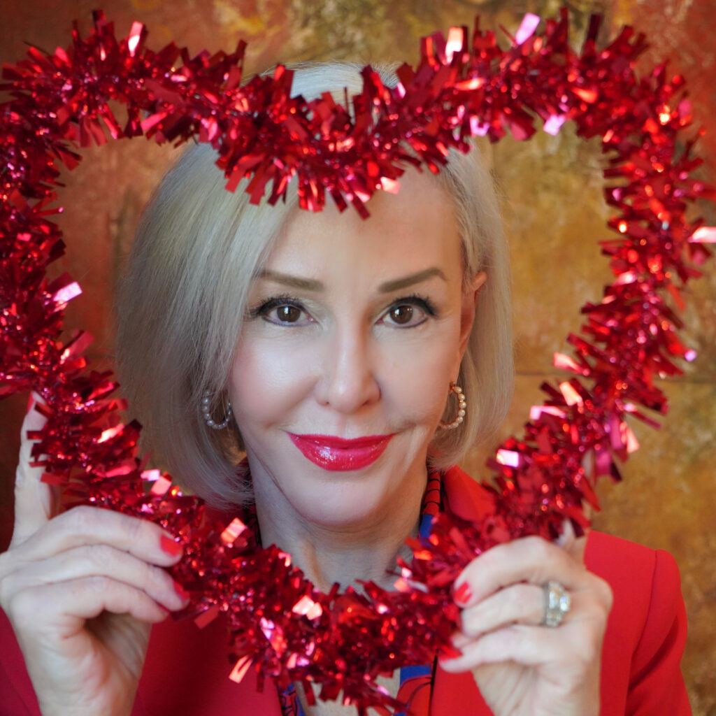 Sheree Frede of the SheShe Show holding a red heart wreath in front of her face